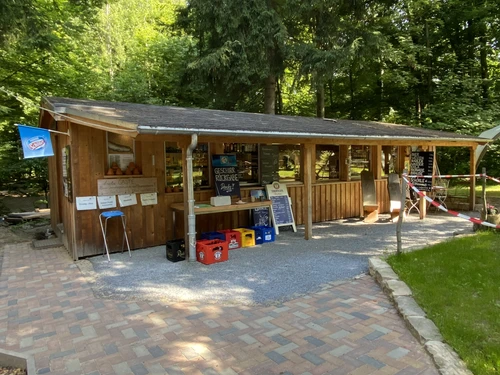 A rustic beer garden with a wooden hut in the forest, beer tables and benches invite you to linger.