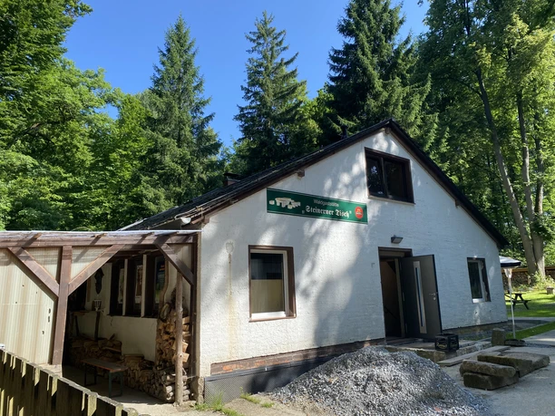 Bergwirtschaft Steinerner Tisch Außenansicht der Waldgaststätte Buitenaanzicht van het bosrestaurant Steinerner Tisch, omgeven door weelderige bomen en natuur.