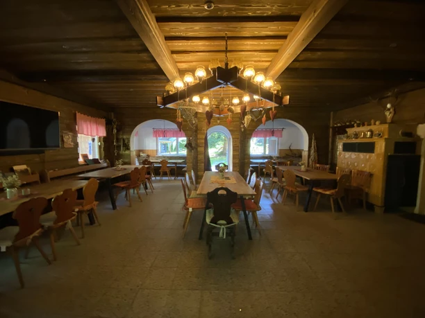 Wood-paneled dining room with long tables and atmospheric lighting under a beamed ceiling.