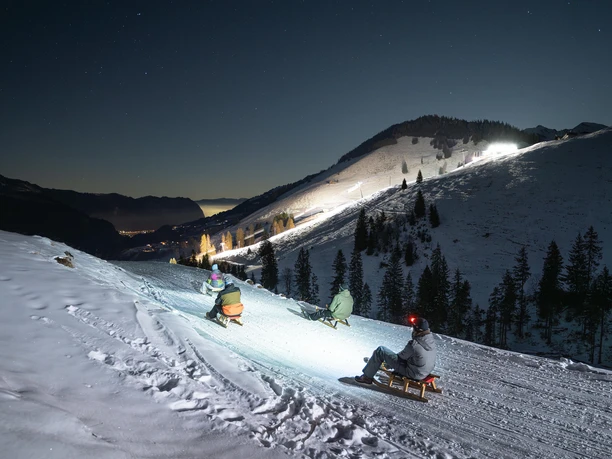 Luge de nuit au Wiriehorn Des lugeurs munis de lampes frontales dévalent le sentier dans la nuit