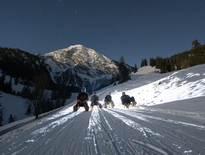 Night sledging at the foot of the Wiriehorn Schlittler von vorne, im Hintergrund das verschneite WiriehornSledgers from the front, the snow-covered Wiriehorn in the backgroundPatineurs de face, en arrière-plan le Wiriehorn enneigé