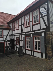 IMG_20220908_113620.jpg Zweistöckiges Fachwerkgebäude mit schiefergedecktem Dach und weißen Wänden, markiert als Ratskeller.