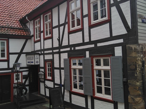 IMG_20220908_113620.jpg Zweistöckiges Fachwerkgebäude mit schiefergedecktem Dach und weißen Wänden, markiert als Ratskeller.