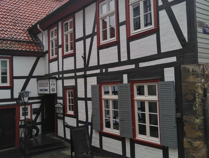 IMG_20220908_113620.jpg Zweistöckiges Fachwerkgebäude mit schiefergedecktem Dach und weißen Wänden, markiert als Ratskeller.