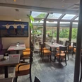 1000086999.jpg Ein helles, modernes Restaurant mit Panoramafenstern, buntem Interieur und üppigem Außenblick.