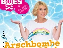 Mirja Boes steht lächelnd vor einem blauen Wasserhintergrund mit textlicher Phrase "Arschbombe Ole!".