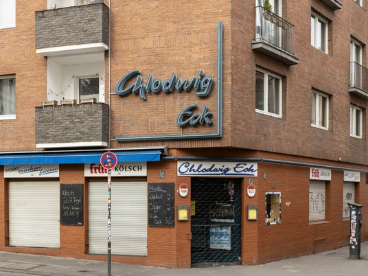 Chlodwig Eck Das Bild zeigt die Backsteinfassade der Eckkneipe "Chlodwig Eck" in Köln mit blauer Neonaufschrift.The picture shows the brick façade of the corner pub "Chlodwig Eck" in Cologne with blue neon lettering.