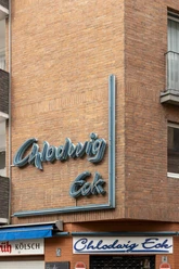 Chlodwig Eck Neonschriftzug "Chlodwig Eck" an einem Backsteingebäude, leicht verwittert, darunter das Eingangsschild.