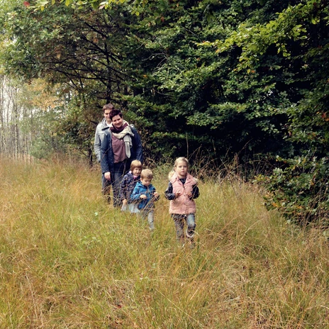Walderlebnispfad Fullener Wald bei Meppen - Herbstspaziergang einer Familie ©Naturpark Moor-Veenland (27).jpg Familie spaziert im herbstlichen Wald durch hohes Gras zwischen Bäumen im Naturpark Moor-Veenland.