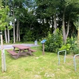 Rastplatz Ströhen Ein idyllischer Rastplatz mit Picknicktisch, Bäumen und Infotafel, umgeben von üppigem Grün.