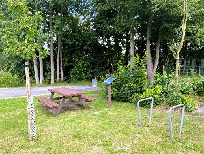 Rastplatz Ströhen Ein idyllischer Rastplatz mit Picknicktisch, Bäumen und Infotafel, umgeben von üppigem Grün.