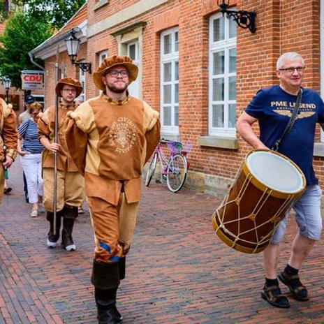 UnterhaltsameTourenMitLerneffekt5.jpg Menschen in historischen Kostümen und ein Trommler ziehen musizierend durch eine Altstadtgasse.