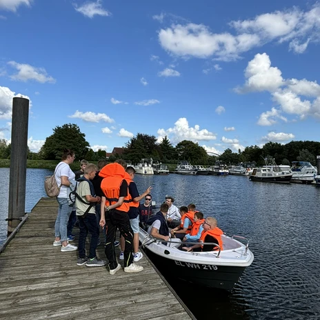 WasserheldenEmsland17.jpg Gruppe Jugendlicher mit Schwimmwesten steigt an einem Bootssteg im Emsland in ein Motorboot.