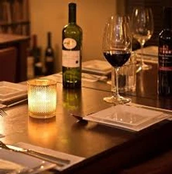 Dinner - Im Restaurant Cozy restaurant ambience with candlelight, laid tables, bottles of wine and filled glasses.
