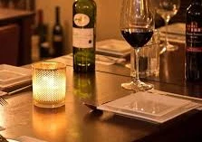 Dinner - Im Restaurant Gemütliches Restaurantambiente mit Kerzenlicht, gedeckte Tische, Weinflaschen und gefüllte Gläser.Cozy restaurant ambience with candlelight, laid tables, bottles of wine and filled glasses.