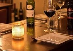 Dinner - Im Restaurant Gemütliches Restaurantambiente mit Kerzenlicht, gedeckte Tische, Weinflaschen und gefüllte Gläser.