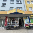 Asia Shop.jpg Zu sehen ist das Schaufenster und die Eingangstür des Asia Shops. Davor stehen Körbe mit frischen Lebensmitteln.