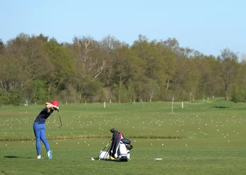 golf-dithmarschen-tourismus Person beim Golfschwung auf weiter Übungsfläche