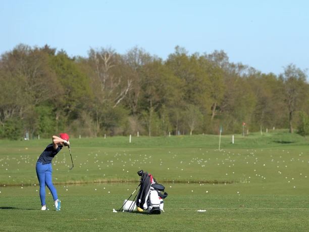 golf-dithmarschen-tourismus Person beim Golfschwung auf weiter Übungsfläche