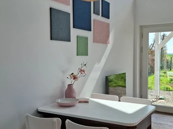 Finkennest Bild 2.jpg Essbereich mit Holztisch und zwei weißen Stühlen, dekorative Bilder an der Wand und Ausblick in den Garten.