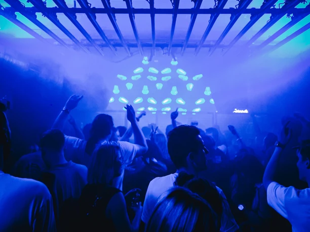 Bootshaus Dreherei The picture shows a lively club scene with people dancing under blue lighting and a metallic grid.