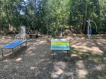 Kinderspielplatz Am Speukebusch Ein kleiner, schattiger Waldpfad mit Sportgeräten vor dichtem Grün verstreut.