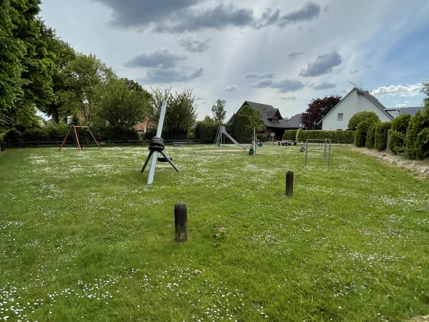 Spielplatz Auf dem Flage Grüne Wiese mit Spielplatz am Horizont. Wenige Wolken am Himmel. Kinder- und Spielgeräte sichtbar.