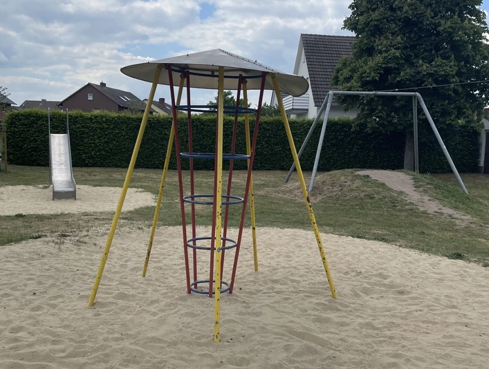 Metall-Klettergerüst mit Rutsche und Schaukel in einem Sandkasten auf einem Spielplatz.