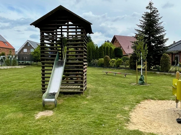 Specker Straße Auf dem Bild ist ein Spielplatz mit einer Rutsche zu sehen, umgeben von Rasen und einigen Bäumen.