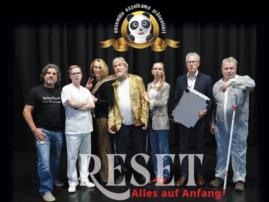 Ensemble Espelkamp, Neues Theater Auf dem Bild ist eine Gruppe von sieben Menschen auf einer Bühne zu sehen. Einige von ihnen lächeln in die Kamera. Im Hintergrund steht der Schriftzug "RESET - Alles auf Anfang!" prominent im Vordergrund.