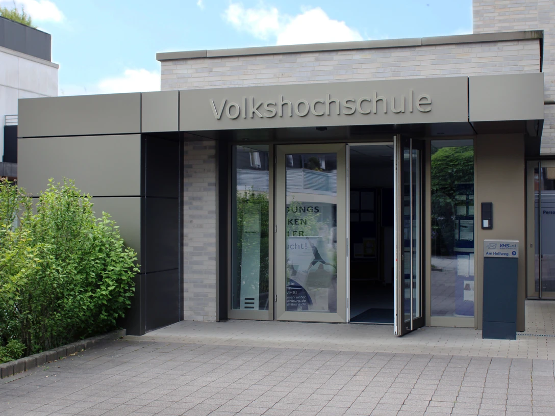 Moderner Eingang einer Volkshochschule mit barrierefreien Zugangsrampen und automatischen Türen.