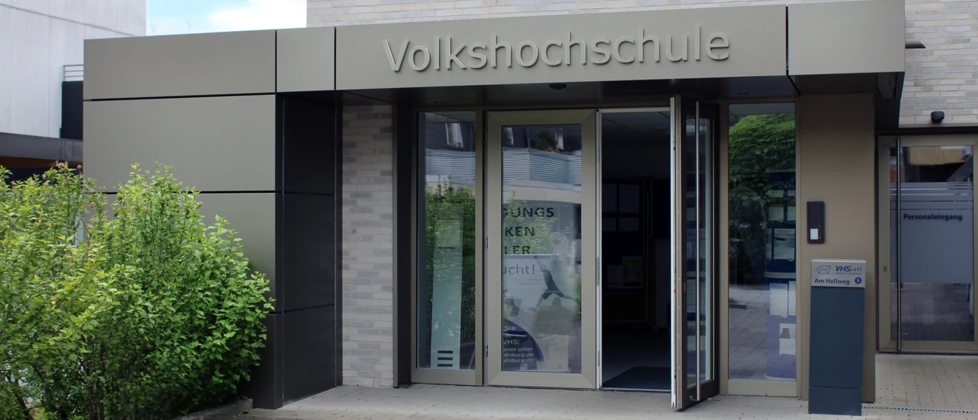 Moderner Eingang einer Volkshochschule mit barrierefreien Zugangsrampen und automatischen Türen.