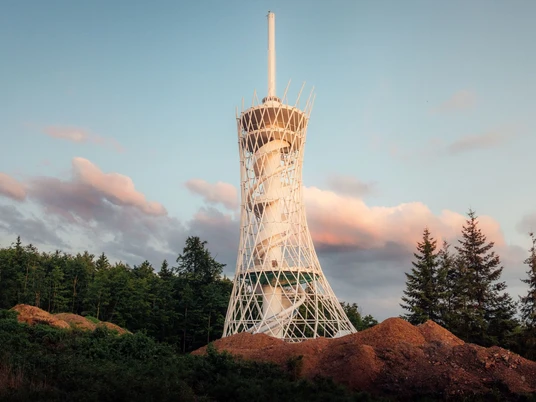 HEX Erlebniswelt Turm im Frühling Der HEX-Aussichtsturm mit spiralförmiger Struktur steht in Ellrich vor kontrastreichem Himmel im Südharz.