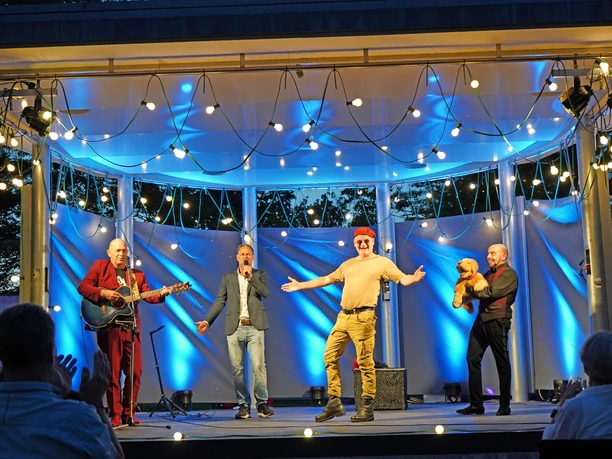 Comedy2025.jpg Vier Comedians stehen bei Dämmerung auf beleuchteter Bühne