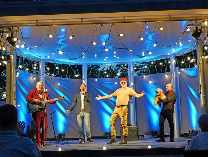 Comedy2025.jpg Vier Comedians stehen bei Dämmerung auf beleuchteter Bühne