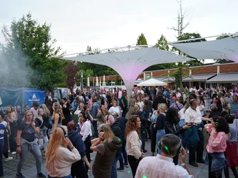 DSC00235.JPG Menschen tanzen mit Kopfhörern bei einer Silent-Disco im Freien unter modernen Lichtsegeln.