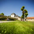 Paderborner-Land_Radfahren_Dalheim_020 ©Kreis Paderborn, Sabrinity.jpg Radfahrer genießen eine Pause auf einer Bank vor historischem Kloster Dalheim bei strahlendem Sonnenschein.