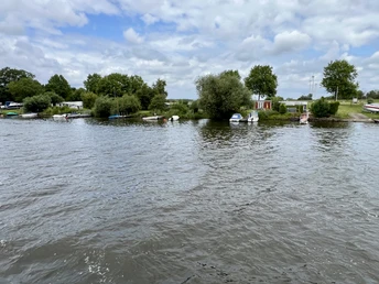 Auf einem Flussabschnitt mit kleinen Booten und üppigem Grün bietet ein Ufer einen friedlichen Ausblick.