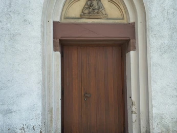 Katholische Kirche St. Bartholomäus zu Haarbrück Holztür der St. Bartholomäus Kirche mit Relief einer Frau in Gewand über dem gotischen Eingang.