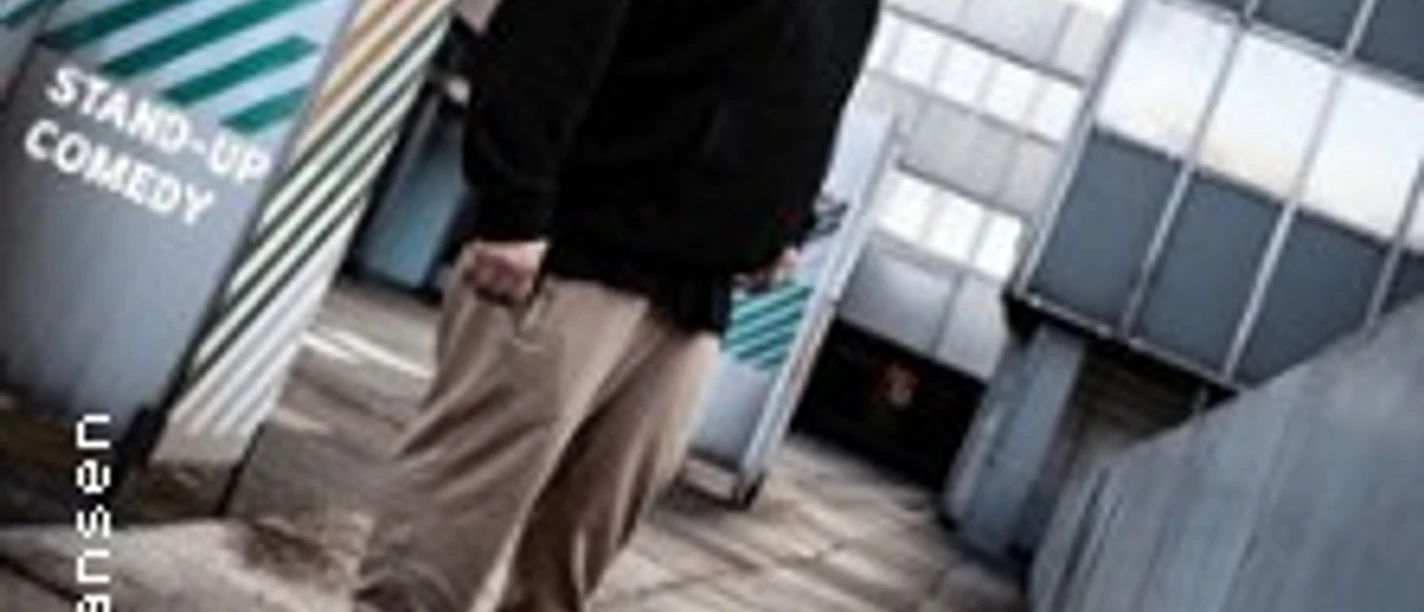 Ein humorvoller Entertainer steht lächelnd auf einer urbanen Dachterrasse.