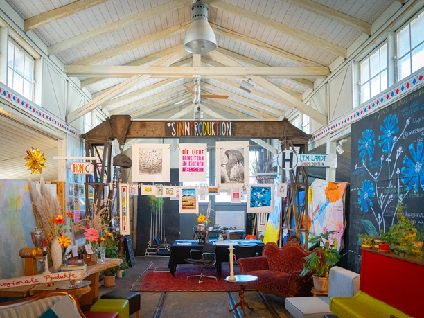 Kunstecke im Biolden Gemütlicher und heller Innenraum des Bioladens mit regionaler Kunst und Sitzmöglichkeiten.