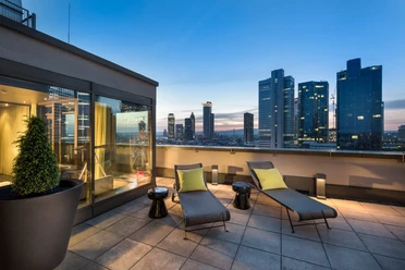 Hotelsuite mit angeschlossender Dachterasse im Adina Apartment Hotel Frankfurt Neue Oper Dachterrasse mit Liegen und Skylineblick bei Sonnenuntergang