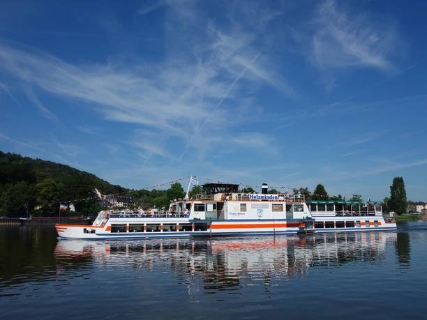 Het passagiersschip Flotte Weser glijdt over het kalme wateroppervlak, omgeven door een blauwe lucht.