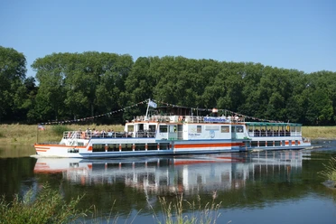 Flotte Weser Das Ausflugsschiff Flotte Weser fährt auf einem Fluss, gesäumt von grünen Bäumen.