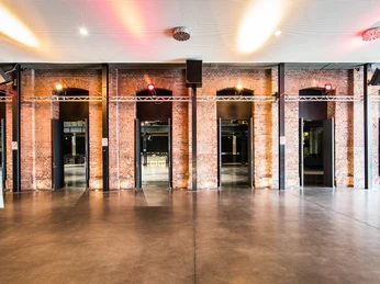 Palladium Köln Foyer Das Palladium Köln Foyer zeigt sich mit industriellem Flair. Sichtbares Mauerwerk, hohe Bögen und moderne Lichtelemente verleihen dem Raum eine besondere Atmosphäre.The Palladium Cologne foyer has an industrial flair. Visible brickwork, high arches and modern lighting elements give the room a special atmosphere.