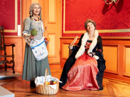 Barocke Begegnung: Marktfrau und Hofdame im Celler Schloss Zwei Frauen in historischen Kostümen im Celler Schloss: eine als Marktfrau mit Korb, die andere als Hofdame mit Fächer vor barocken Porträts