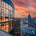 TOWER185/FIFTY HEIGHTS Glasfassade eines Hochhauses mit Blick auf Frankfurts Skyline bei Sonnenuntergang.