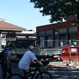 bünde-bahnhof-foto.jpg Zwei Personen mit Fahrrädern vor modernem Gebäudeensemble am Bahnhof Bünde bei sonnigem Wetter.