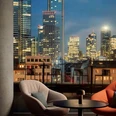 Seating area with chairs and tables in front of city skyline at night