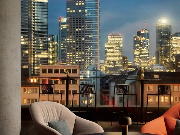 Seating area with chairs and tables in front of city skyline at night